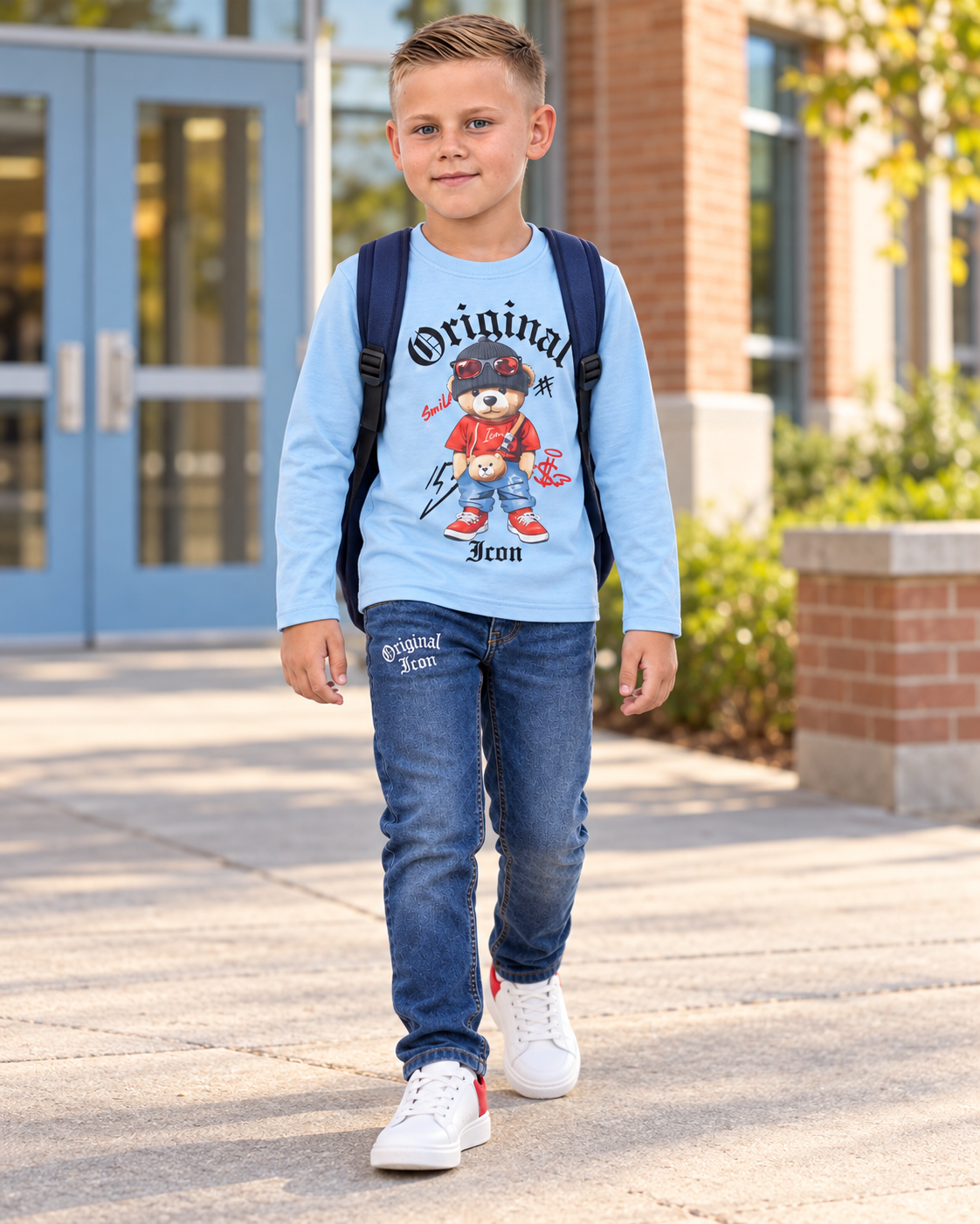 Jayce draagt een lichtblauwe ICON Original top met teddyprint en bijpassende jeans op een schoolplein.